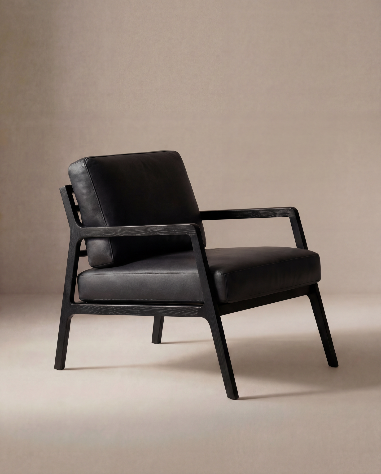The Wooden Stories Nysse Lounge Chair | Leather features a modern black leather seat and backrest, straight solid oak legs and frame, all set against a neutral beige background.