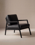 The Wooden Stories Nysse Lounge Chair | Leather features a modern black leather seat and backrest, straight solid oak legs and frame, all set against a neutral beige background.