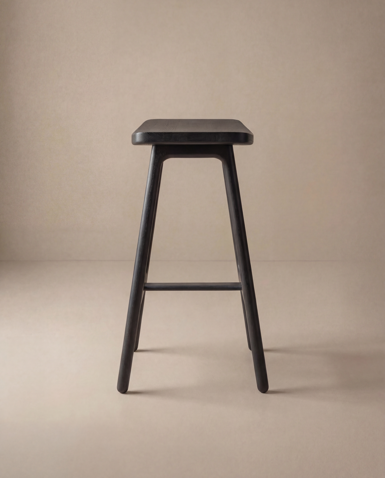 The Odd Counter Stool by Wooden Stories, crafted from solid oak with four legs and a rectangular seat, stands on a neutral beige background, highlighting timeless minimalist design.