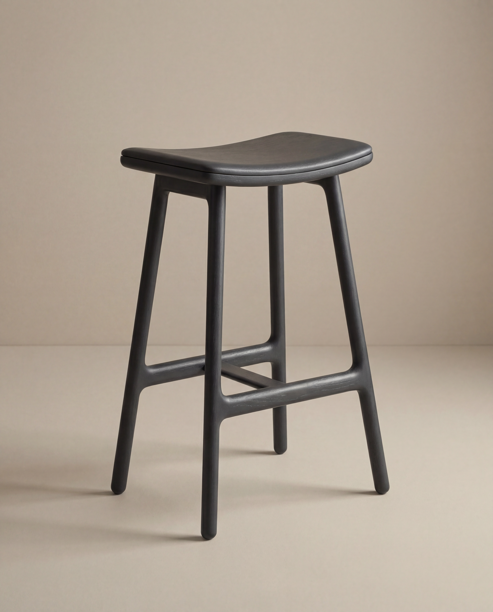 The Odd Counter Stool | Leather by Wooden Stories features a modern design with a curved leather seat and four legs, ideal for kitchen island seating, showcased against a neutral beige background.