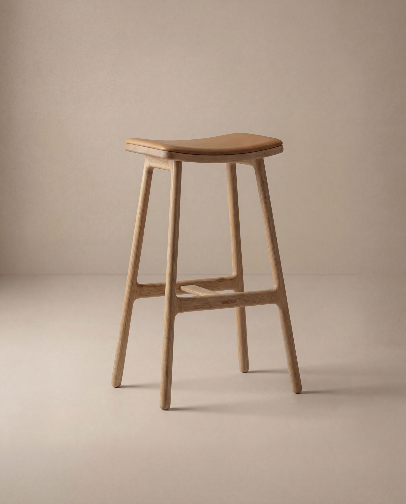 The Odd Counter Stool | Leather by Wooden Stories features a minimalist, modern design with a curved seat, four straight legs, and a natural wood finish—ideal as kitchen island seating and shown against a neutral beige background.