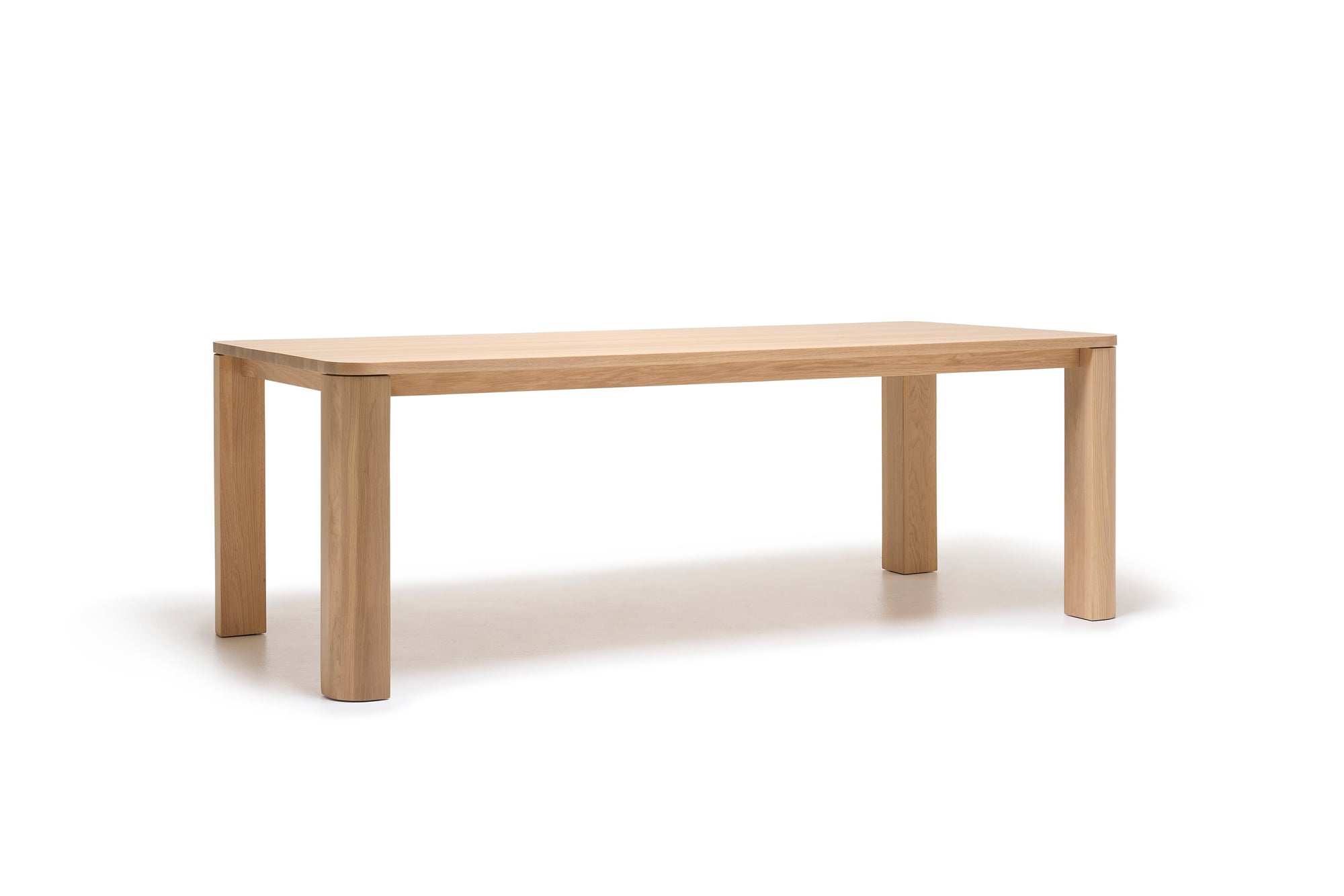The Oli Dining Table by Wooden Stories is a rectangular dining table crafted from solid American oak, featuring four thick legs, a light natural wood finish, and a simple modern design inspired by the Danish collection.