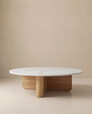The Wooden Stories Pivot Coffee Table | Round - Wood & Stone features a white marble top and solid oak cylindrical base, shown against a plain beige background.