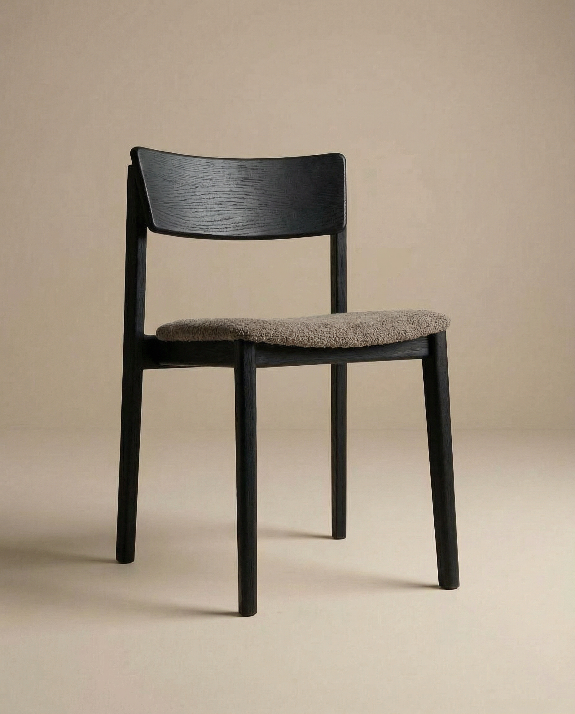 The Poise Dining Chair by Wooden Stories features a black oak frame, curved rectangular backrest, and a textured light brown fabric seat, embodying minimalist Danish design against a plain beige background.