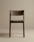 The Poise Dining Chair by Wooden Stories features an espresso oak frame and a textured fabric seat, photographed against a plain beige background.