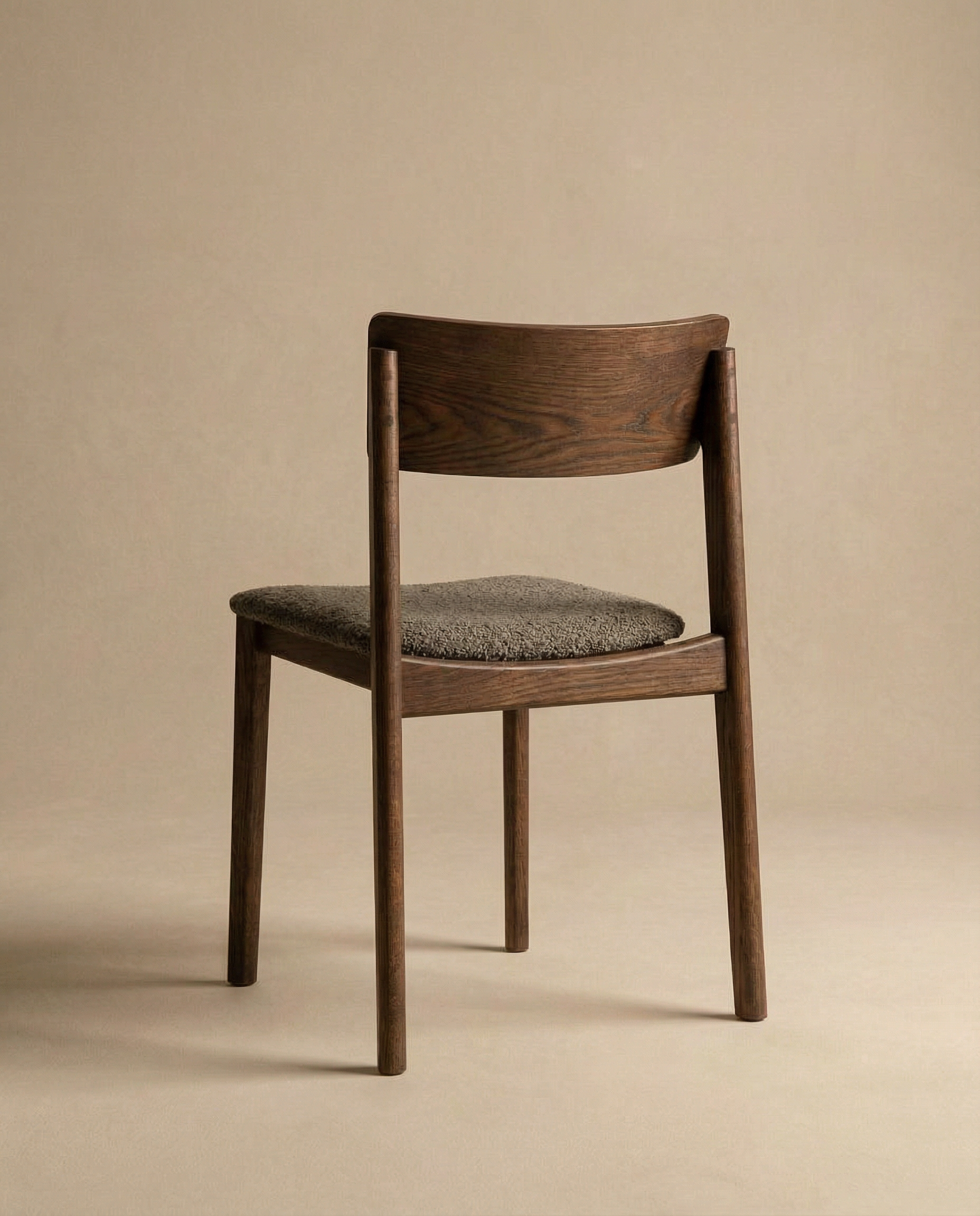 The Poise Dining Chair by Wooden Stories features an espresso oak frame, a curved backrest, and a textured fabric seat, standing on four straight legs against a plain beige background.