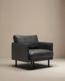 The Pensive Lounge Chair | Leather by Wooden Stories features a modern, black leather design with wide armrests and a boxy silhouette, inspired by mid-century Danish style. It sits on a light beige floor with a matching beige background.