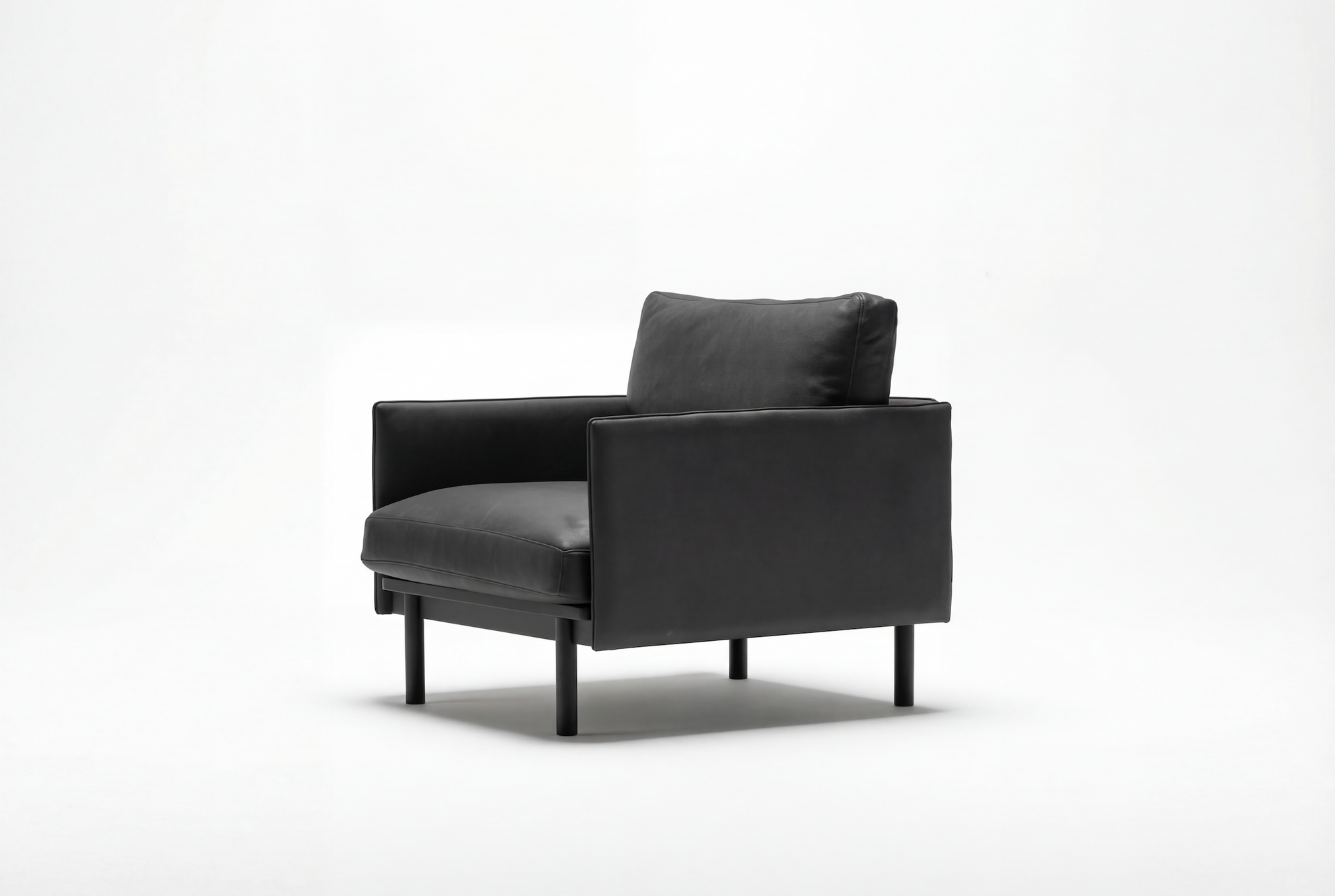 The Pensive Lounge Chair | Leather by Wooden Stories is a modern black armchair with Danish lines, featuring a padded seat and backrest, slim legs, and a minimalist, contemporary design against a plain white background.