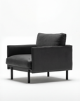 The Pensive Lounge Chair | Leather by Wooden Stories is a modern black armchair with Danish lines, featuring a padded seat and backrest, slim legs, and a minimalist, contemporary design against a plain white background.