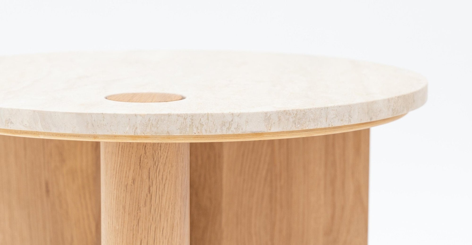 A close-up of the Wooden Stories Pivot Side Table | Light Oak - Stone Top, showcasing its round, contract-grade solid wood base and legs, light stone top, and a circular wooden inlay detail near the edge.