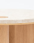 A close-up of the Wooden Stories Pivot Side Table | Light Oak - Stone Top, showcasing its round, contract-grade solid wood base and legs, light stone top, and a circular wooden inlay detail near the edge.
