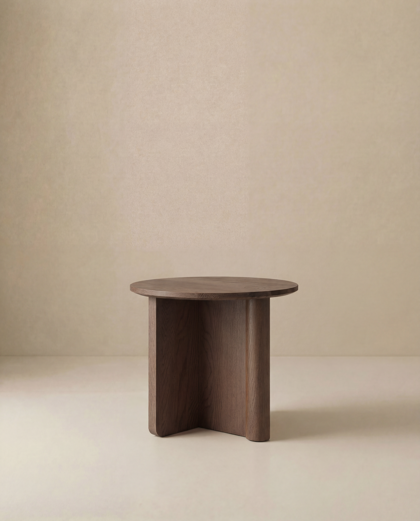 The Wooden Stories Pivot Side Table features a round, solid oak top with a minimalist design and three interlocking legs, shown against a plain beige background.