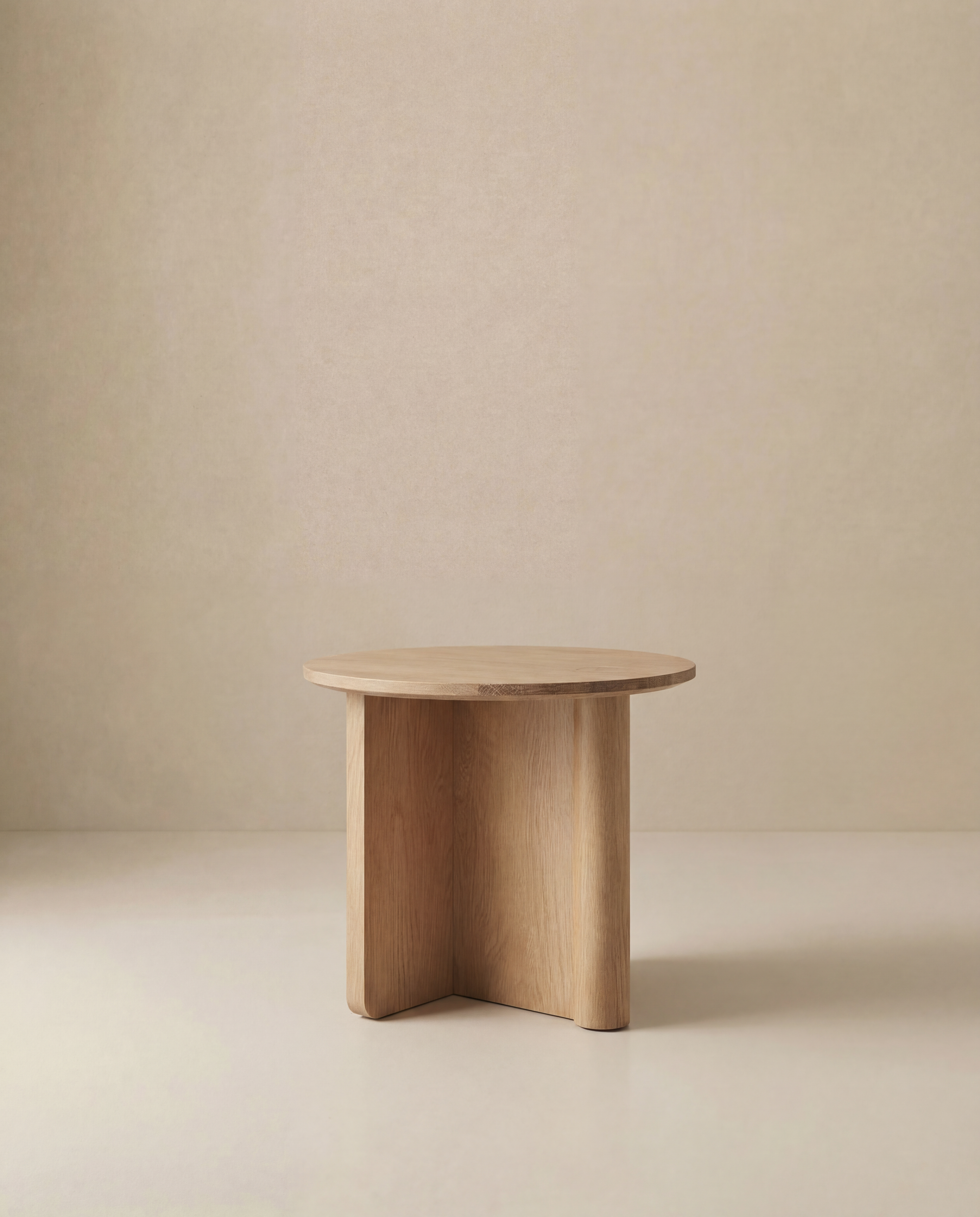 The Pivot Side Table by Wooden Stories features a small, round solid oak top and three thick, intersecting legs, shown against a plain beige background.