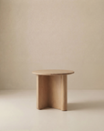 The Pivot Side Table by Wooden Stories features a small, round solid oak top and three thick, intersecting legs, shown against a plain beige background.