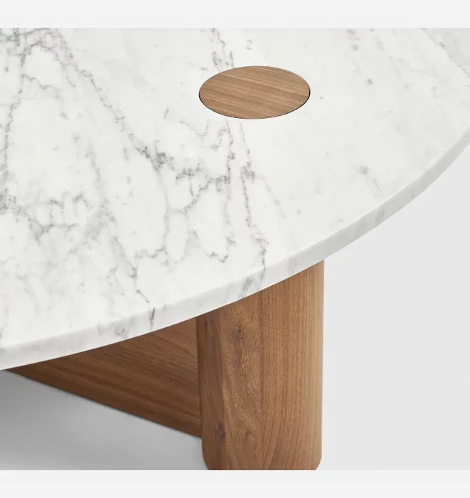 A close-up of the Wooden Stories Pivot Coffee Table - Light Oak, featuring a white honed marble top with gray veining, a circular wood inlay, solid light oak dowel legs, and a sleek modern design.