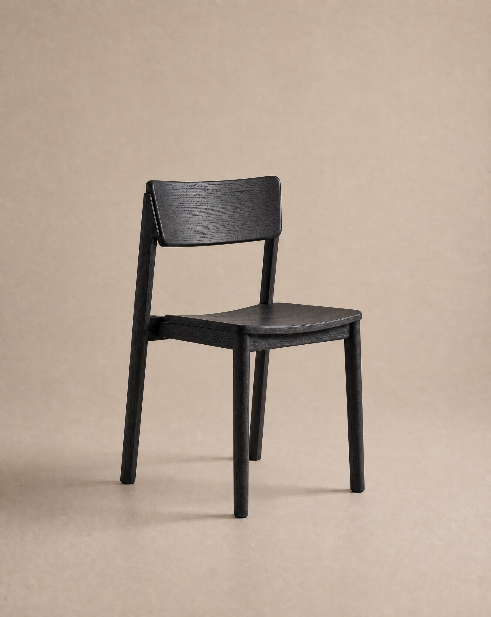 A Poise Dining Chair | Wood by Wooden Stories, crafted with solid oak in a sleek black finish and minimalist design, is showcased against a neutral beige background.