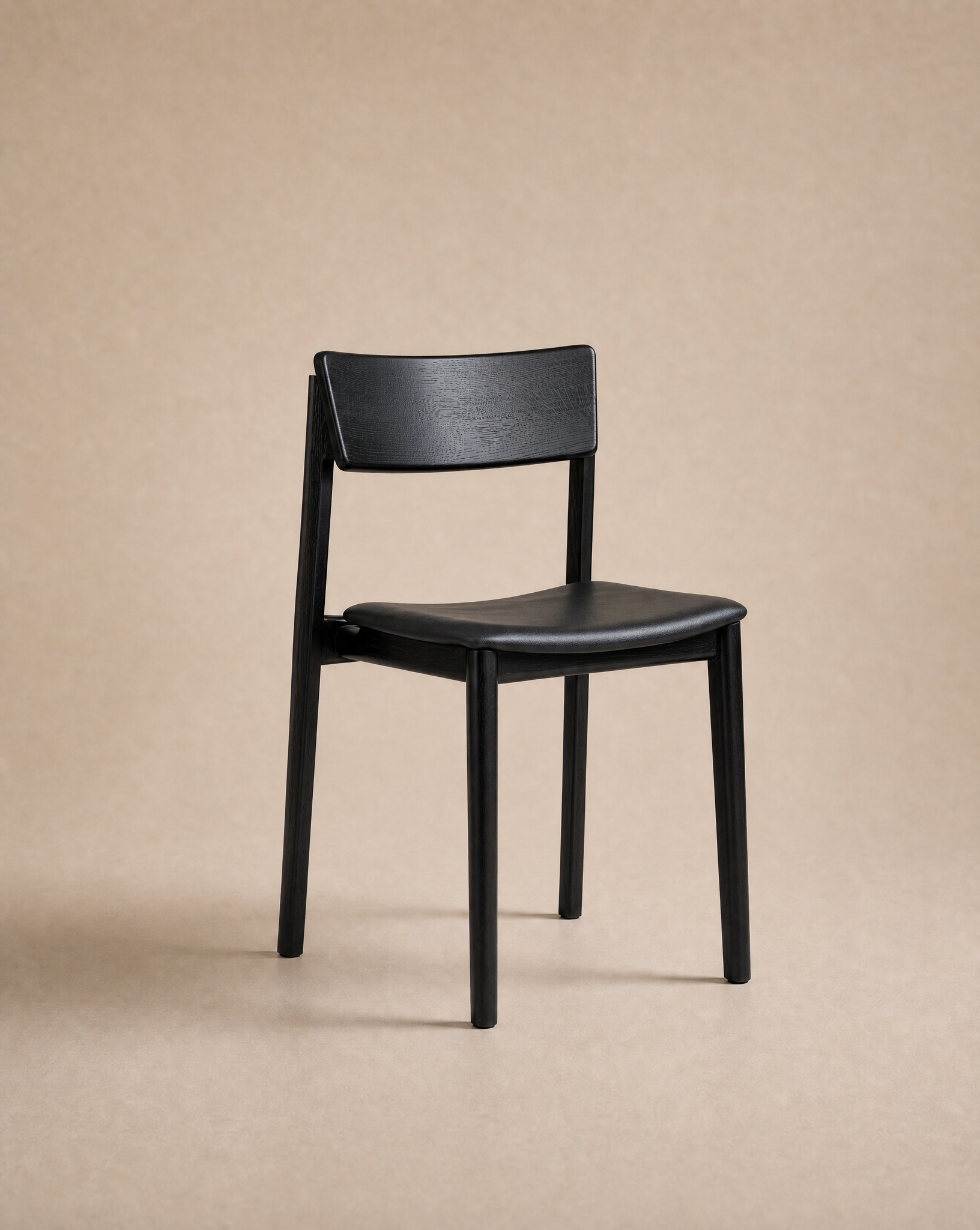The Poise Dining Chair | Leather by Wooden Stories, featuring a simple black solid oak frame with a curved seat and backrest, stands on a neutral beige background, exemplifying the refined craftsmanship of the Wooden Stories collection.