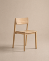 The Poise Dining Chair | Wood by Wooden Stories, featuring a minimalist solid oak design with a straight backrest and no armrests from the Danish Collection, is displayed on a neutral beige background.