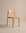 The Poise Dining Chair | Wood by Wooden Stories, featuring a minimalist solid oak design with a straight backrest and no armrests from the Danish Collection, is displayed on a neutral beige background.