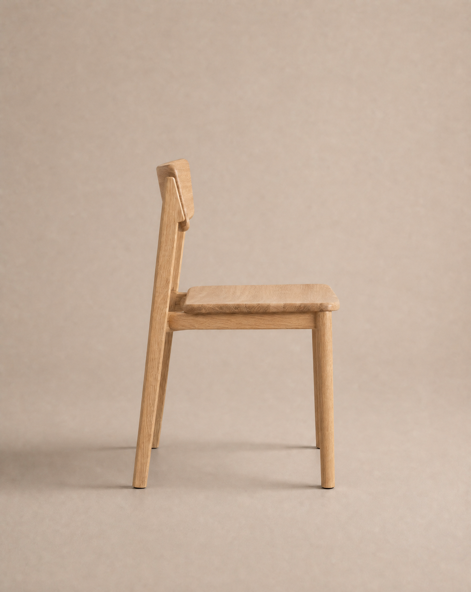 The Poise Dining Chair | Wood by Wooden Stories, featuring a flat seat and straight backrest crafted from solid oak, is displayed in side profile against a plain beige background as part of the Danish Collection.