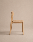 The Poise Dining Chair | Wood by Wooden Stories, featuring a flat seat and straight backrest crafted from solid oak, is displayed in side profile against a plain beige background as part of the Danish Collection.