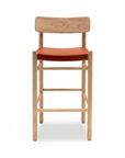 The Cesco Counter Stool by SOBU features solid white ash with a light natural finish, a rectangular backrest, and an orange top grain leather seat, shown against a plain white background.