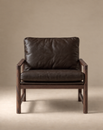 The Troubadour Lounge Chair | Leather by Wooden Stories features dark brown leather and a wooden frame, displayed front-facing against a plain beige background—an icon of mid-century Danish style.
