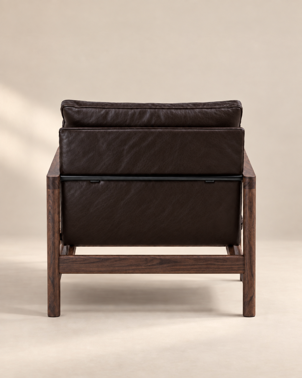 The Troubadour Lounge Chair | Leather by Wooden Stories features dark brown leather and a wooden frame, shown from the back against a neutral beige background.