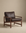 The Troubadour Lounge Chair | Leather by Wooden Stories features a dark brown leather cushion and wooden frame, inspired by Danish design, set against a neutral beige background.