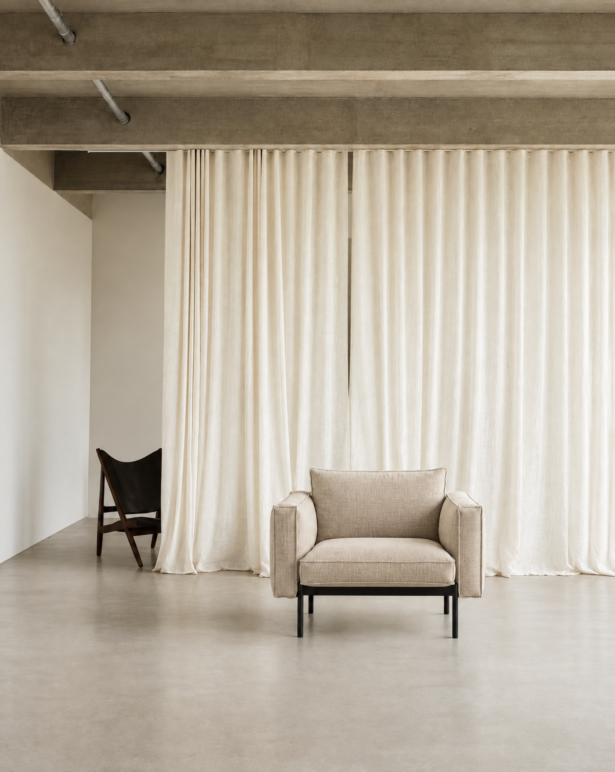 Attendant Lounge Chair | Fabric in beige upholstery with a black frame, centered in a room with floor-to-ceiling curtains.