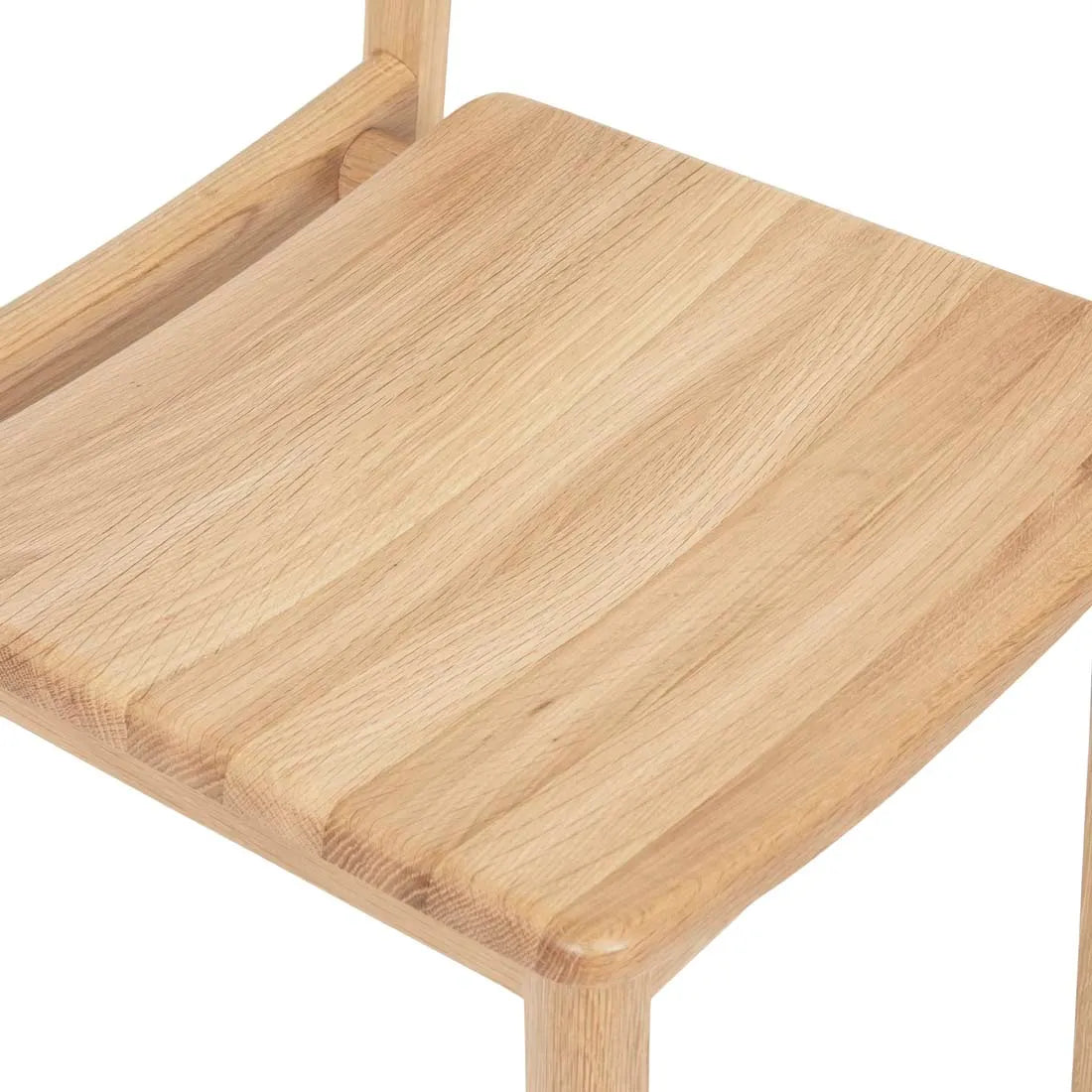 A close-up of the Poise Dining Chair | Light Oak by Wooden Stories highlights the visible wood grain on the seat and part of the contract-grade frame and legs.