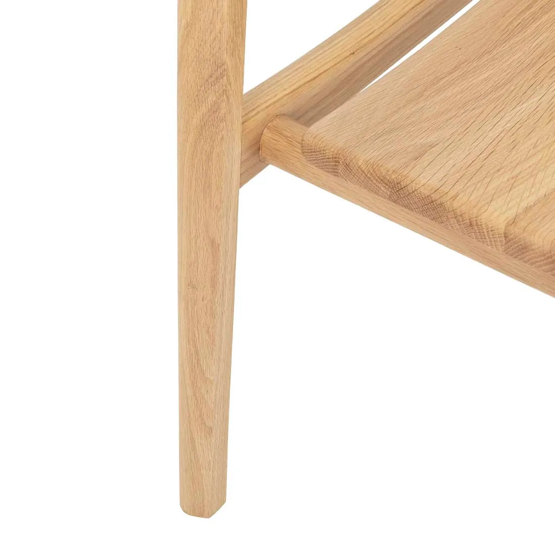 Close-up of a light oak leg from the Wooden Stories Poise Dining Chair, seamlessly attached to a matching shelf with visible wood grain and a smooth finish.