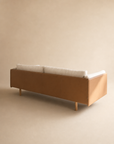 The Sonder Sofa | Fabric with Leather Back by Wooden Stories, featuring high-density foam cushions and a modern tan Danish design, is shown from the back against a plain beige background.