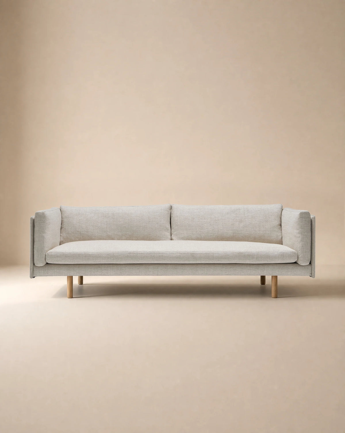 A light beige, low-profile Sonder Sofa | Fabric with thin armrests and light-colored wooden legs from the Danish collection.