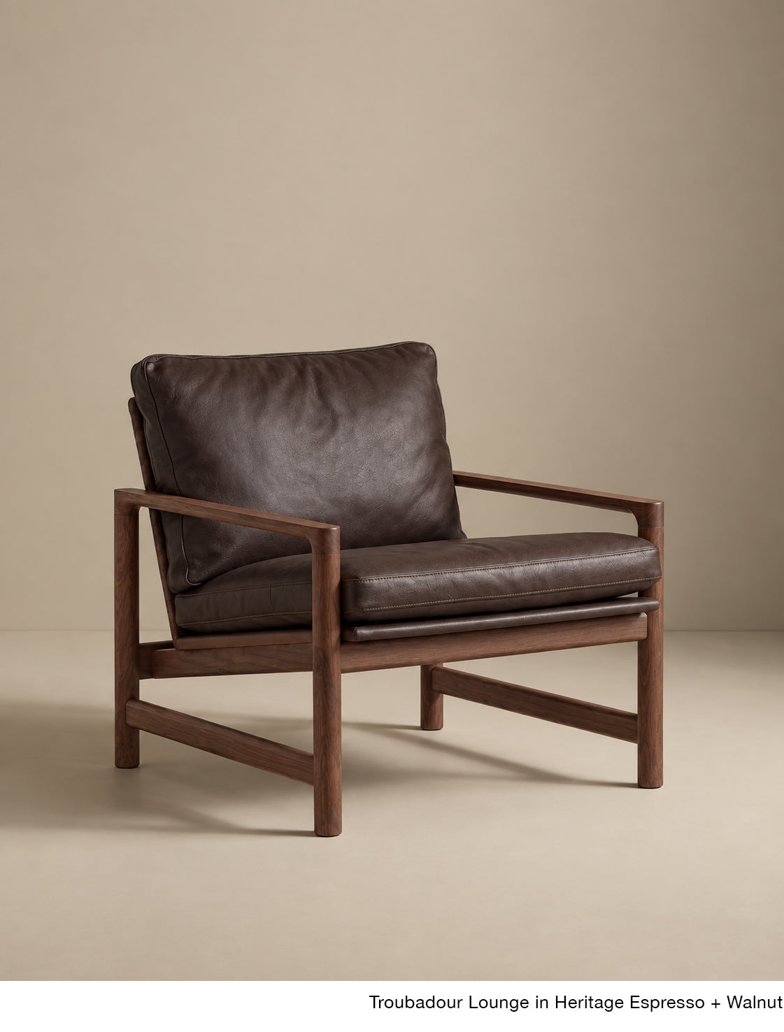 The Troubadour Lounge Chair | Leather by Wooden Stories features a dark brown leather cushion and walnut frame, with clean lines, a wide seat, and angled armrests inspired by Danish design on a neutral background.