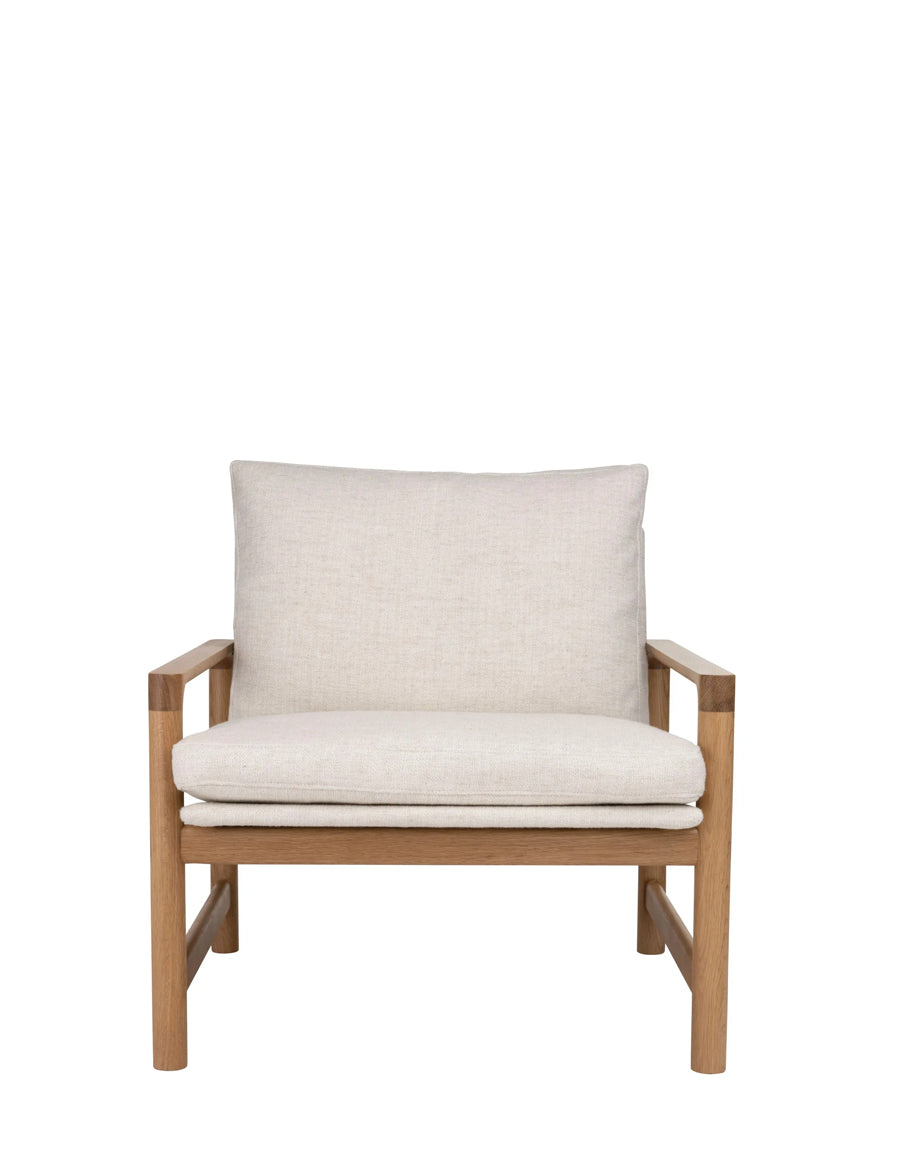 The Troubadour Lounge Chair | Fabric by Wooden Stories is a modern armchair inspired by the Danish collection, featuring a light wood frame and cream-colored cushions, presented against a plain white background.