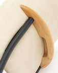 Close-up of the Solace Dining Chair | Leather by Wooden Stories—an upholstered chair with a light beige backrest, curved solid wood handle, and black metal frame shown against a white background.