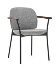 The Solace Dining Armchair | Fabric by Wooden Stories features a gray upholstered seat and backrest, black metal legs, and wooden armrests—a minimalist, contemporary design ideal for modern spaces.
