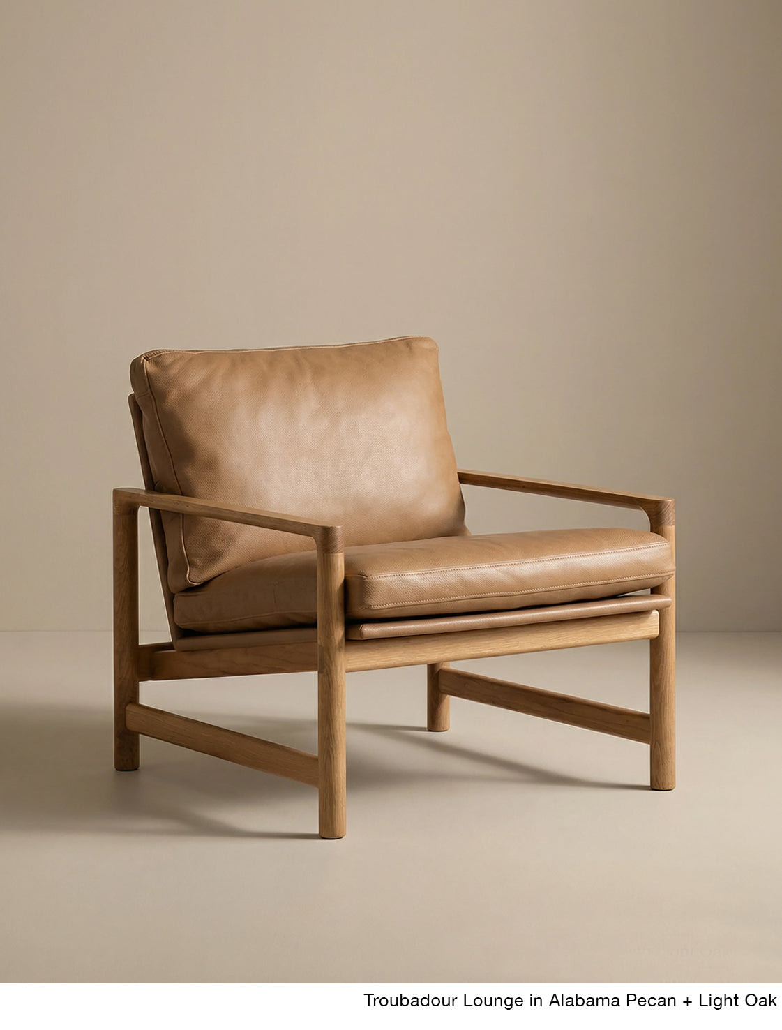 The Troubadour Lounge Chair | Leather by Wooden Stories features a light oak frame and tan leather cushions, shown against a plain beige background.
