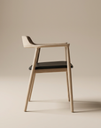 The SOBU Sven Dining Chair in White Ash with a leather padded seat features a modern minimalist design, curved backrest, and slim legs, shown set against a neutral beige background.