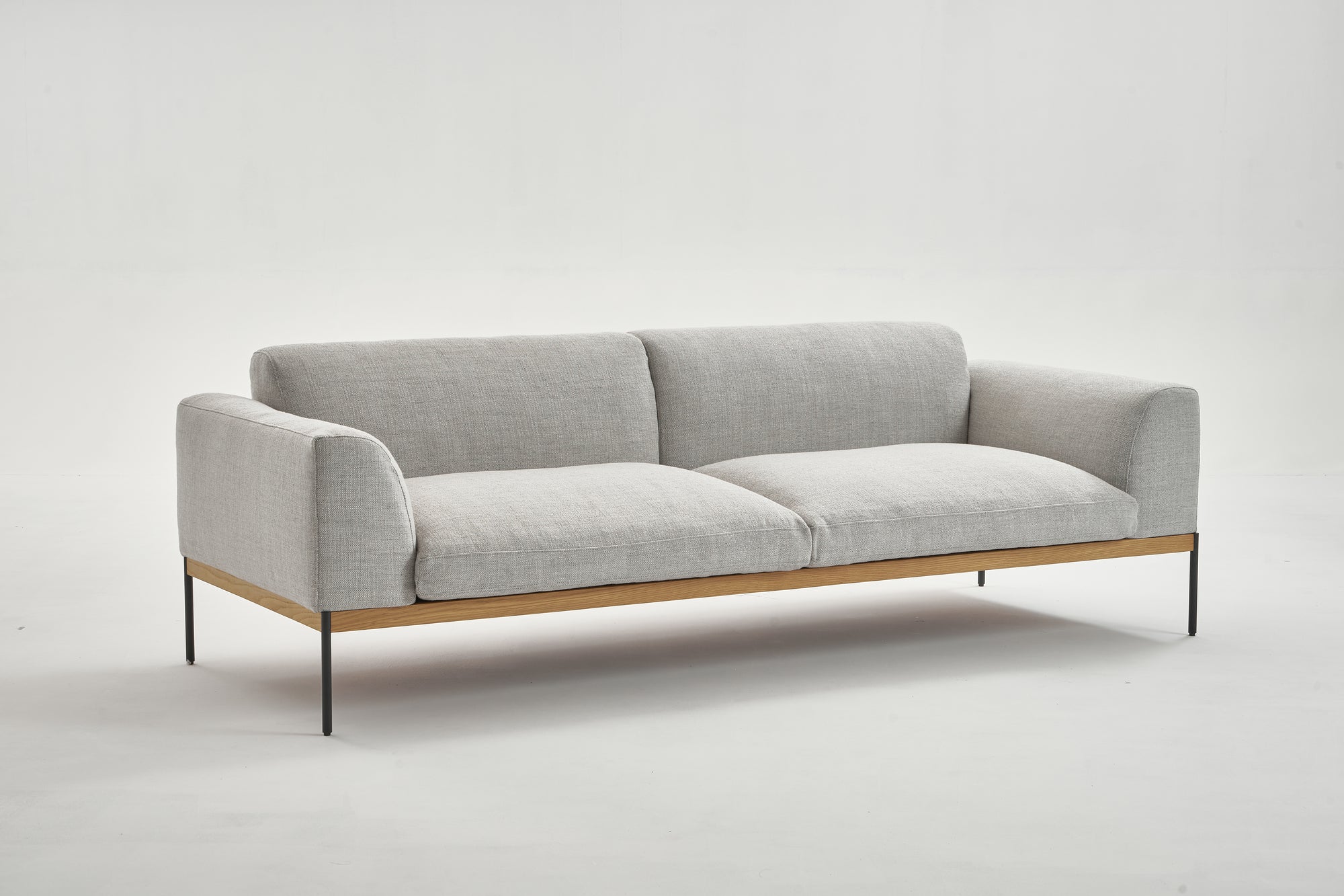 The Wooden Stories Department Sofa 93" | Fabric features a modern, minimalist design in light gray fabric, Danish-inspired lines, wooden accents, slim black metal legs, and a solid wood plinth, shown against a plain white background.