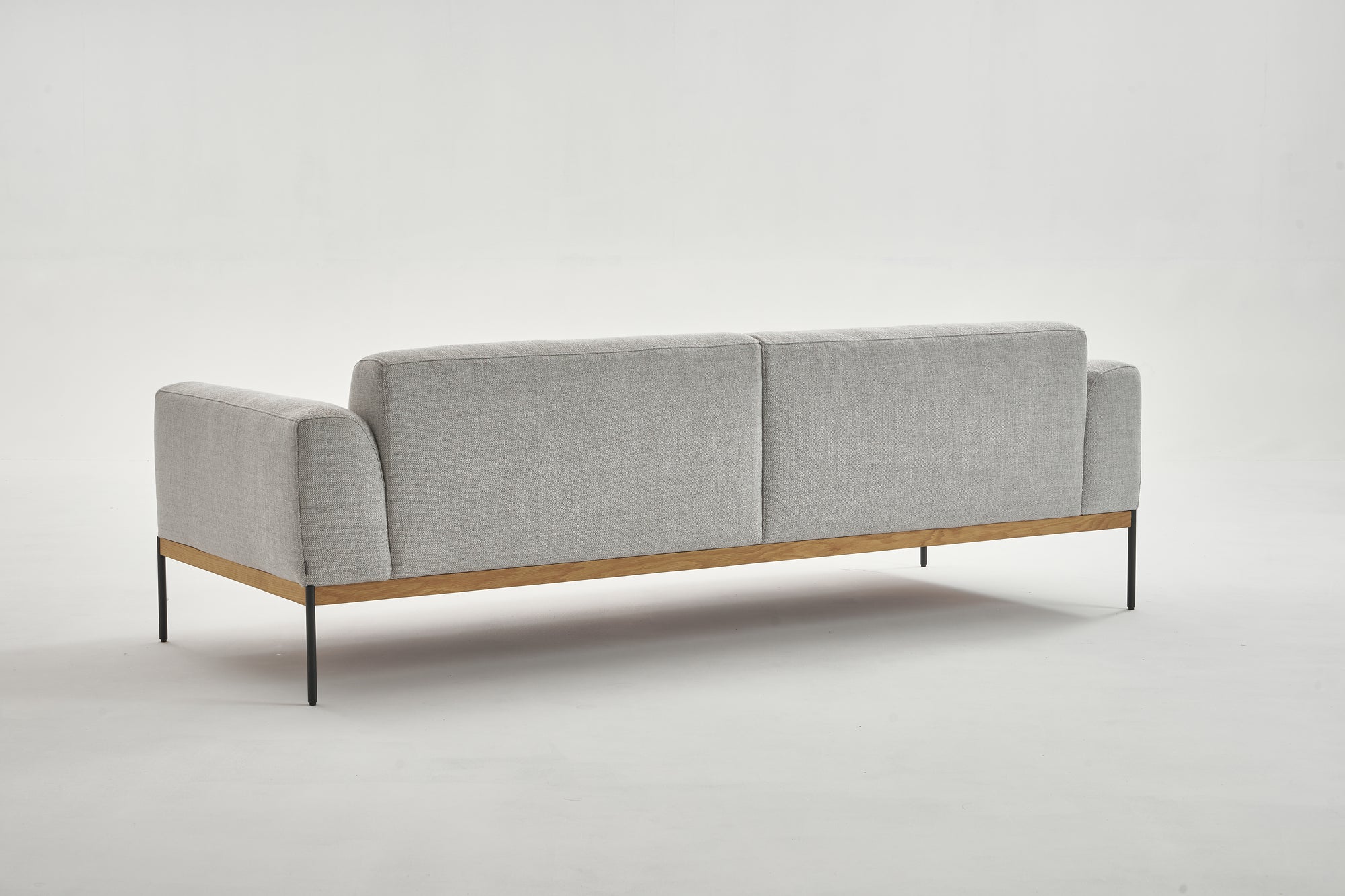 The Wooden Stories Department Sofa 93" | Fabric is a modern light gray piece with Danish lines, solid wood plinth base, and thin black metal legs—ideal for commercial or domestic spaces. Seen from the back against a plain white background.