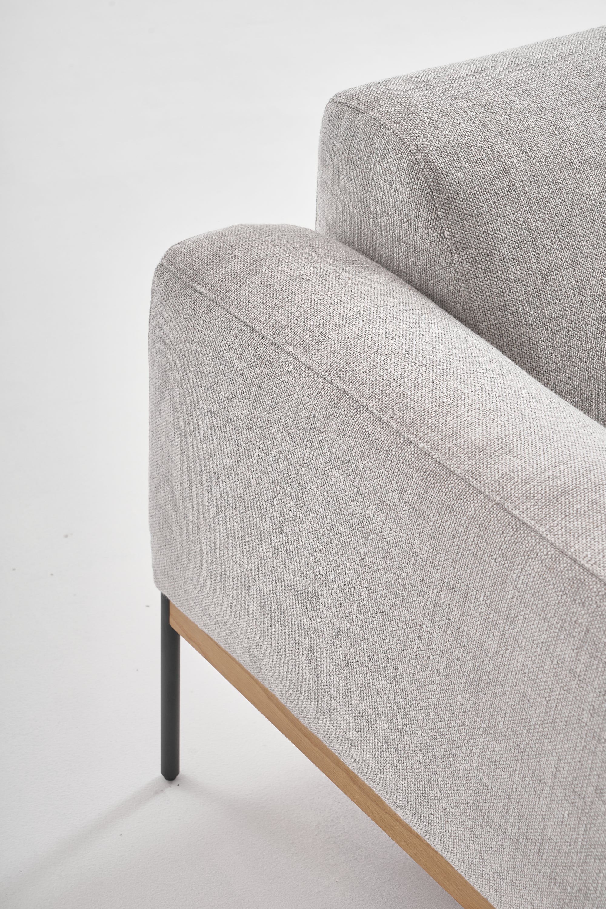Close-up of the Wooden Stories Department Sofa 93&quot; in light gray fabric, featuring Danish lines, a solid wood plinth base, and slim black metal legs, shown against a white background.