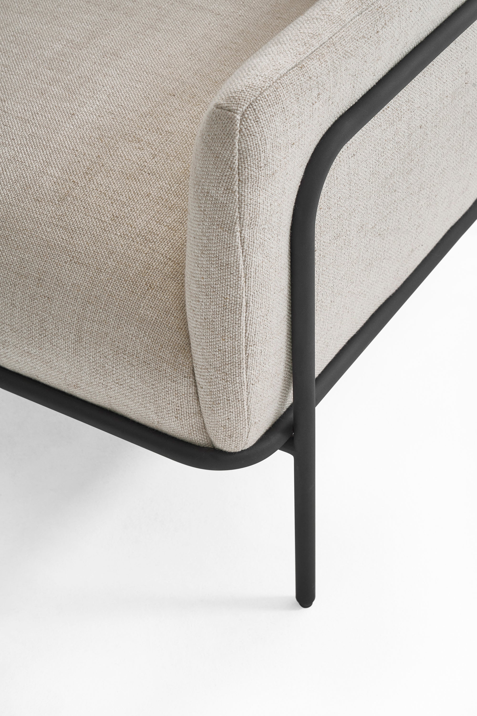Close-up of the Scribe Lounge Chair | Fabric by Wooden Stories, featuring modern beige upholstery and a Bauhaus-inspired metal frame and legs. The image highlights the chair’s corner and minimalist design against a white background.