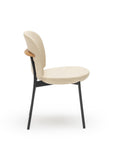 The Solace Dining Chair | Leather by Wooden Stories features a modern beige rounded seat, backrest, black premium steel frame legs, and a wood accent on the back, presented in profile against a white background.