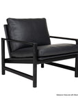 Experience modern minimalism with the Troubadour Lounge Chair | Leather by Wooden Stories. This sleek black lounge chair features a sturdy black metal frame, generously cushioned leather seat and back, and open sides. The squared arms and legs offer a contemporary, Danish-inspired silhouette for a refined yet comfortable addition to your living space.