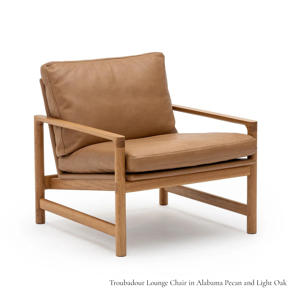 The Troubadour Lounge Chair by Wooden Stories features a solid oak frame, tan leather cushions, and a minimalist open design inspired by classic Danish style.