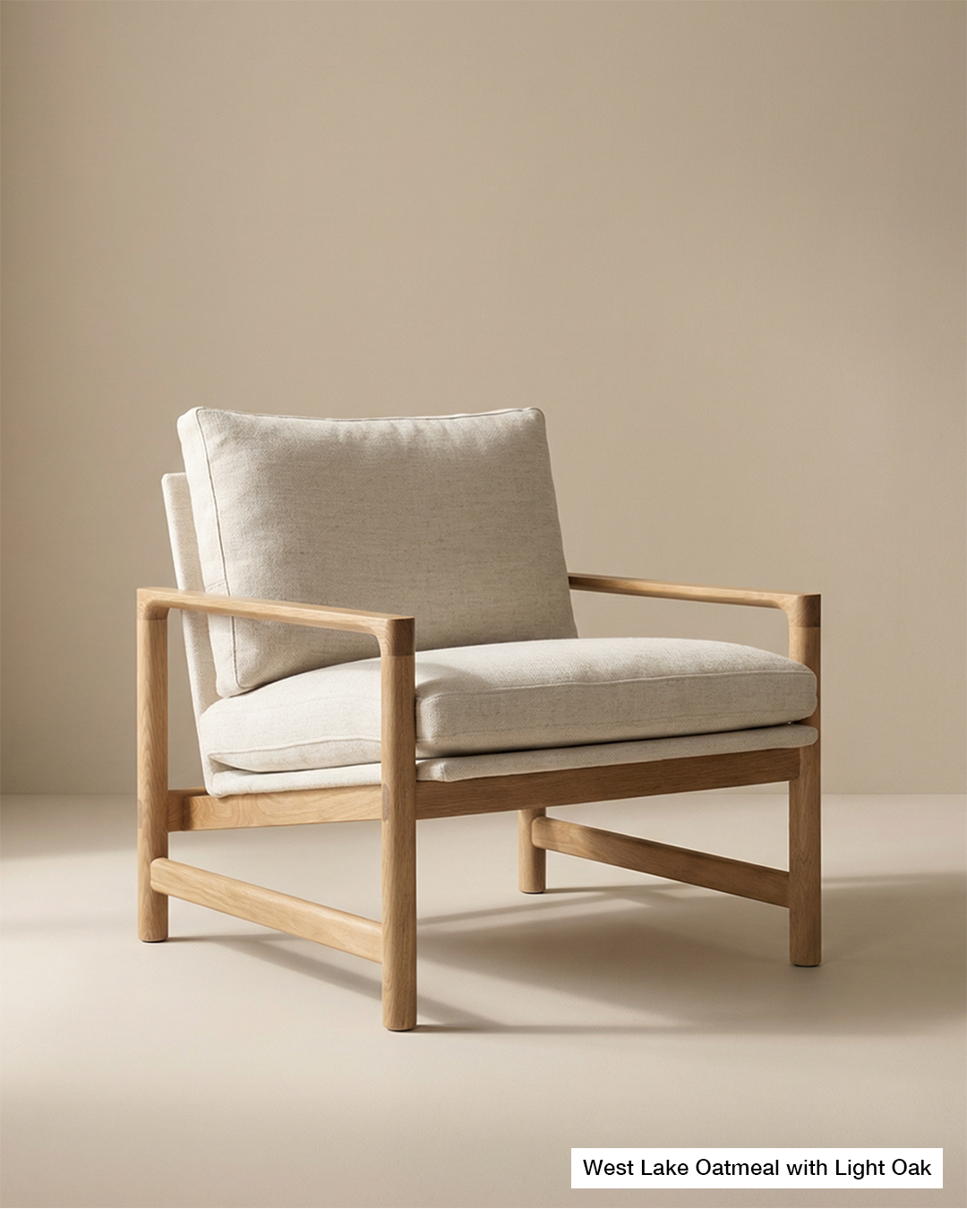 The Troubadour Lounge Chair | Fabric by Wooden Stories features a solid oak frame and beige cushions, showcased against a plain, light-colored background. Part of the Danish Collection, its minimalistic and contemporary design offers a modern lounge seating solution.