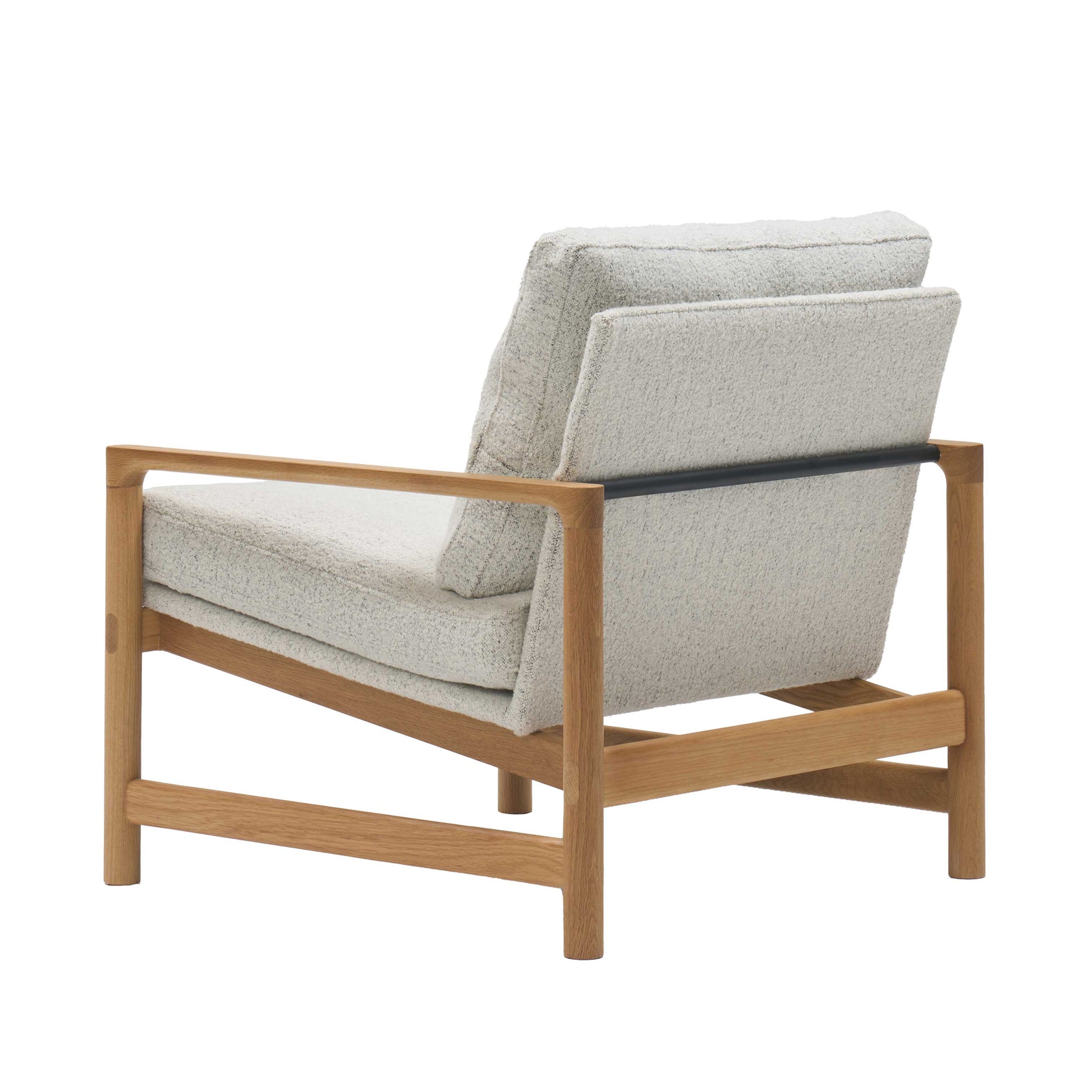 The Troubadour Lounge Chair | Fabric by Wooden Stories features a solid oak frame, sleek black metal support bar, and light gray upholstered cushions, shown from a rear side angle on a white background.