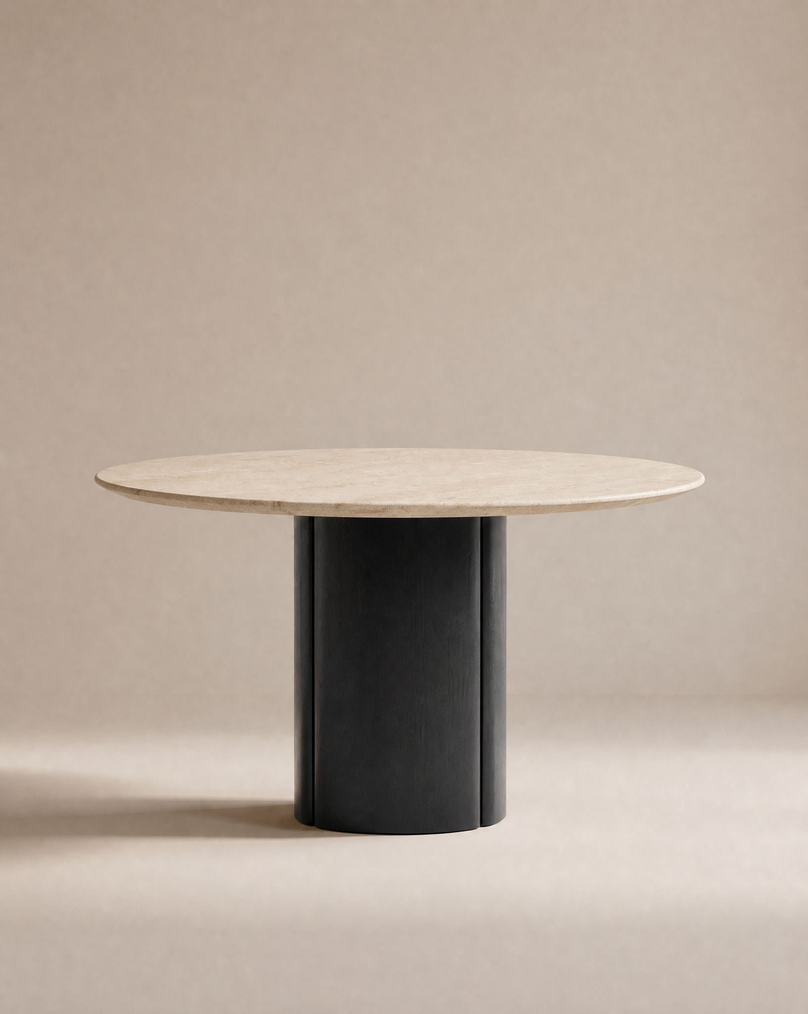 The Tathra Round Dining Table | Stone Top by Wooden Stories features a light beige stone top and a thick, cylindrical black base, crafted to contract grade standards and shown against a plain neutral background.